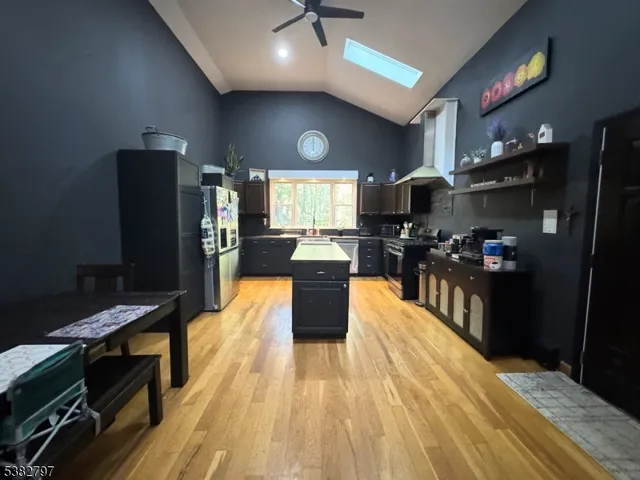 a kitchen with stainless steel appliances granite countertop a refrigerator a stove top oven and a dining table with wooden floor