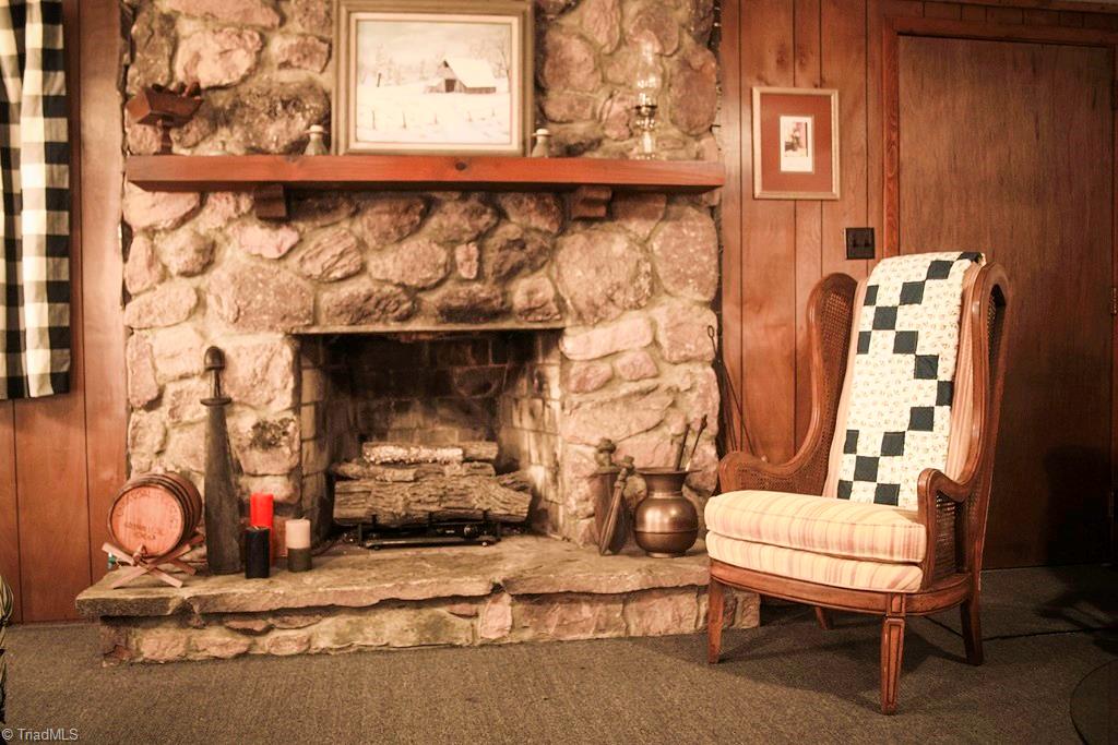 47 Ridge Road Glade Valley, NC 28627 - Photo 25 of 25 Not one, but 2 stone fireplaces in this home! This one is on the lower level. The door goes outside to the patio beneath the deck. There are several windows to let in lots of natural light.