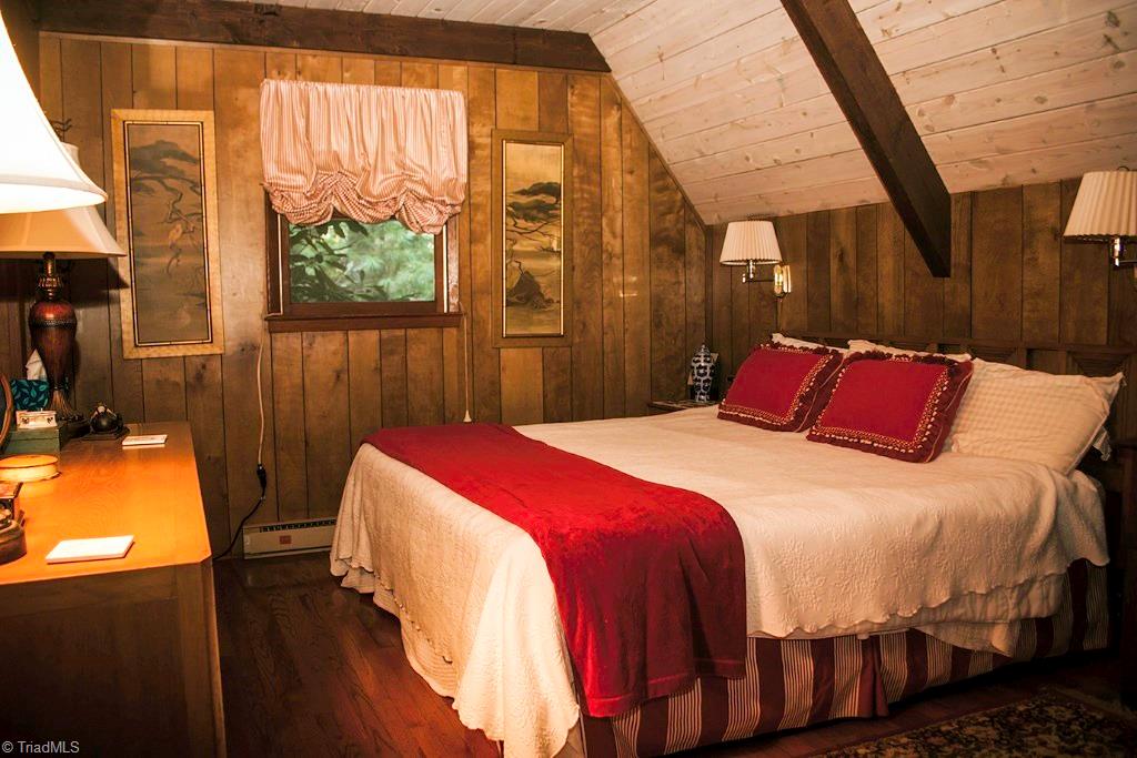 47 Ridge Road Glade Valley, NC 28627 - Photo 6 of 25 The master bedroom is charming with hardwood floors, a sizable closet, and bedside reading lamps.