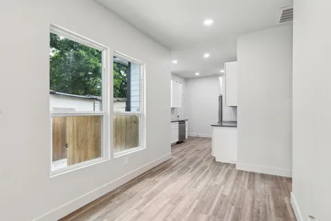 a view of a big room with wooden floor kitchen view and windows