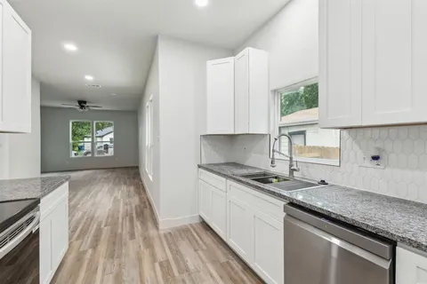 a kitchen with granite countertop a sink stove and cabinets