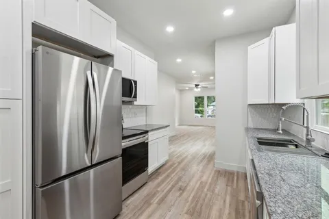 a kitchen with a refrigerator a sink and wooden floor