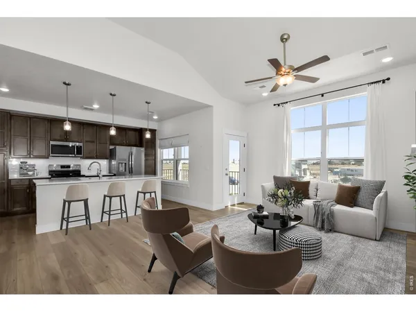 a view of an empty room with wooden floor and a kitchen