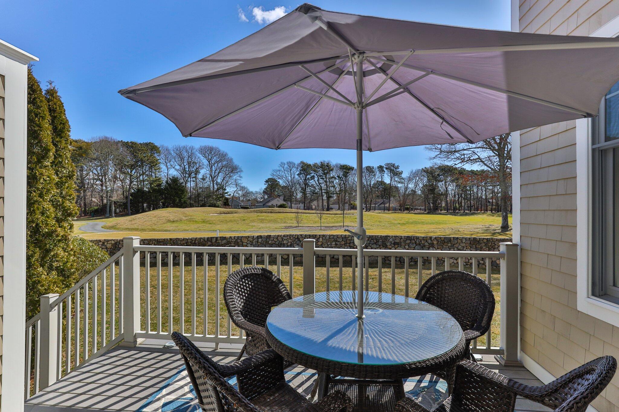 16 Quinns Way Mashpee, MA 02649 - Photo 33 of 59 a view of a balcony with a table and chairs under an umbrella