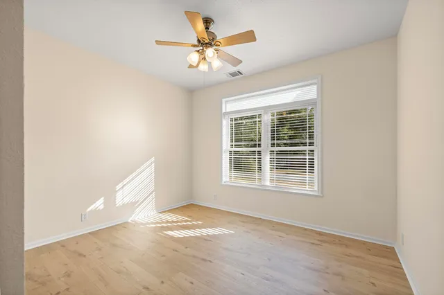 an empty room with a window and a ceiling fan