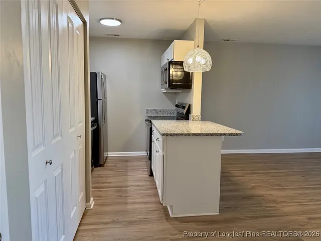 a kitchen with stainless steel appliances granite countertop a sink a refrigerator and a wooden floor