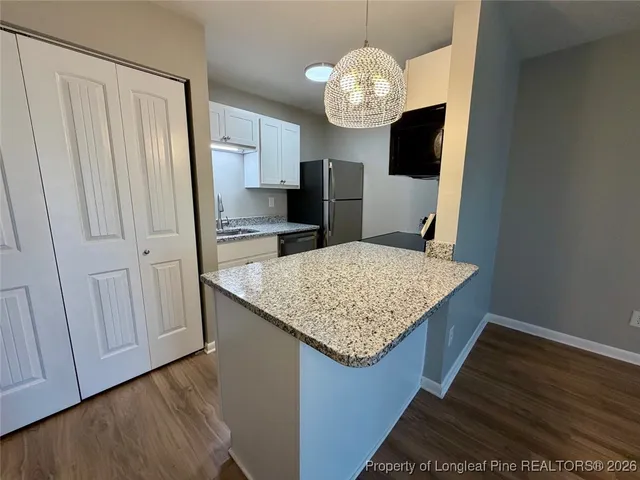 a kitchen with granite countertop a refrigerator and a stove top oven