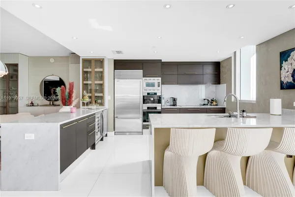 a kitchen with kitchen island a counter top space a sink stainless steel appliances and cabinets