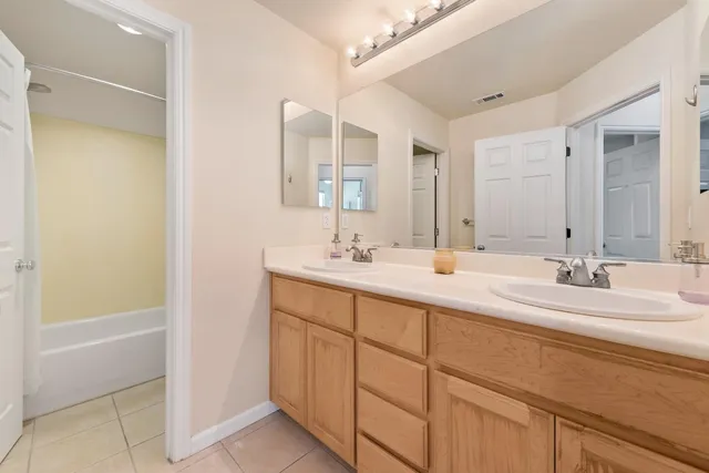 a bathroom with a double vanity sink a mirror and a bathtub
