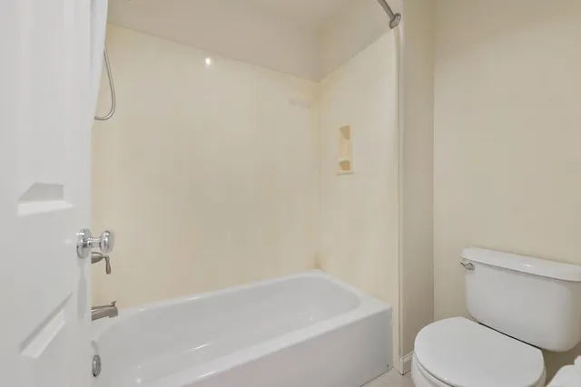 a white toilet sitting next to a bath tub