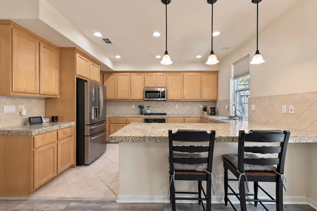 a kitchen with a refrigerator a stove a sink and chairs