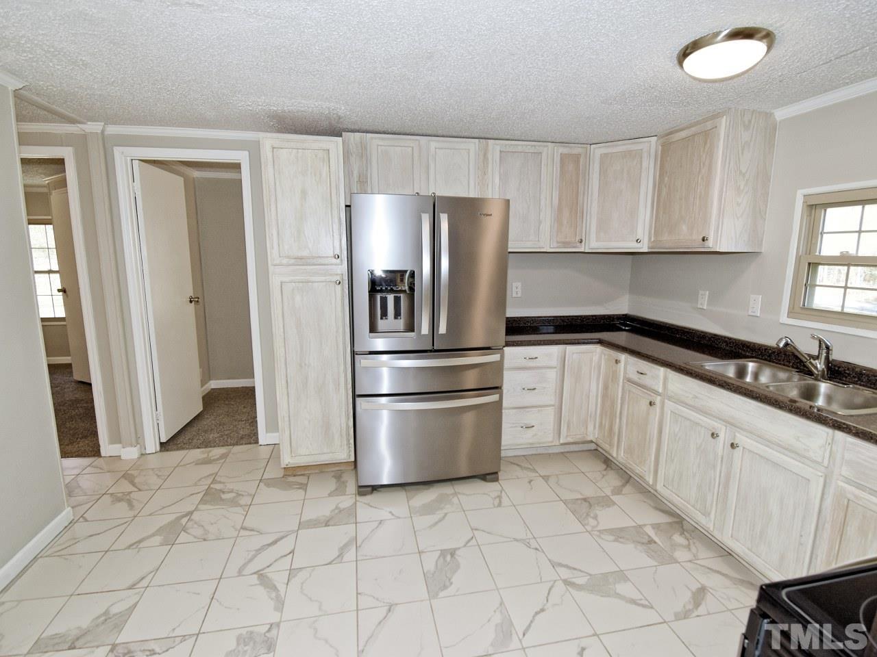 810 Dink Ashley Road Timberlake, NC 27583 - Photo 6 of 31 a kitchen with granite countertop a refrigerator and a sink