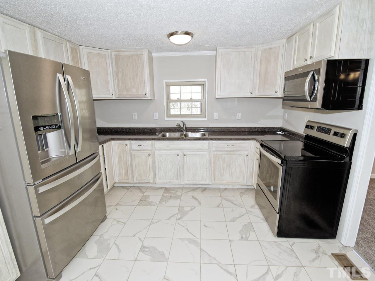 810 Dink Ashley Road Timberlake, NC 27583 - Photo 7 of 31 a kitchen with white cabinets stainless steel appliances and a sink