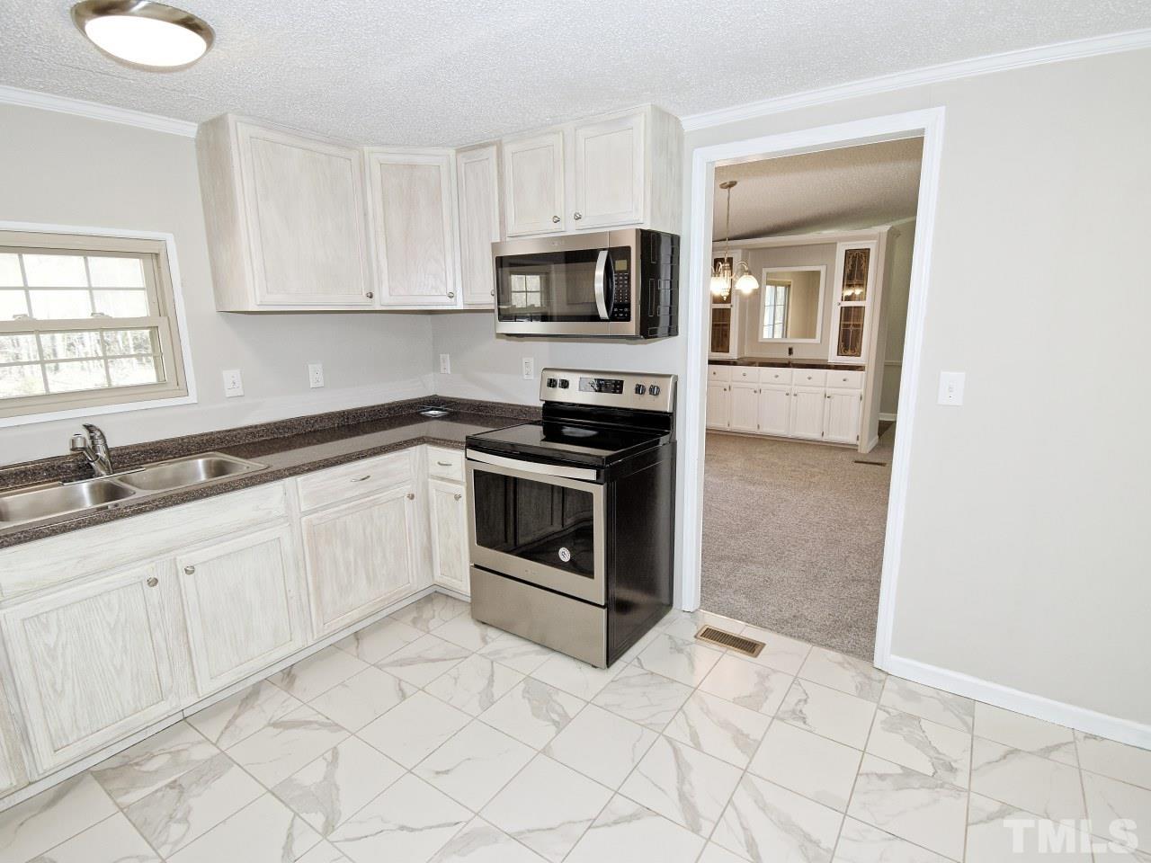 810 Dink Ashley Road Timberlake, NC 27583 - Photo 8 of 31 a kitchen with granite countertop white cabinets stainless steel appliances and a sink