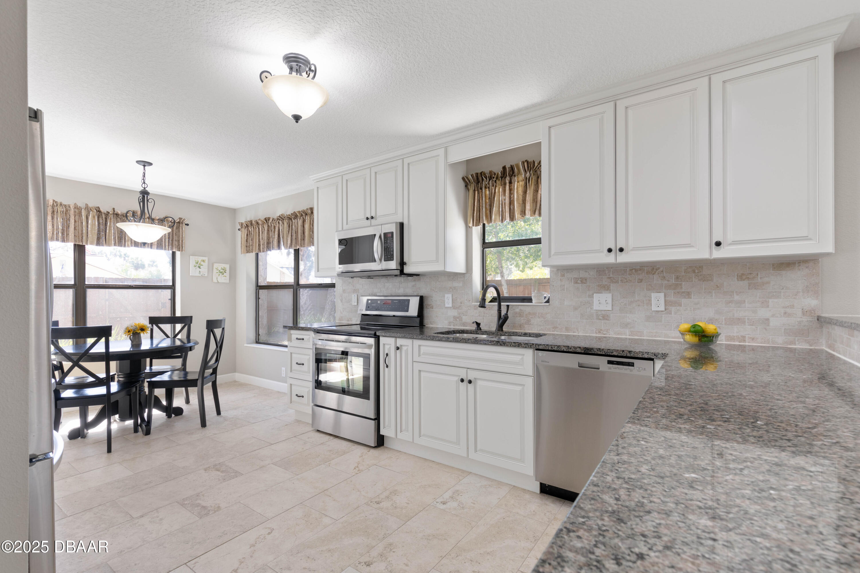 792 Victoria Circle East Ormond Beach, FL 32174 - Photo 14 of 53 a kitchen with stainless steel appliances granite countertop a stove top oven a sink a dining table and chairs with wooden floor