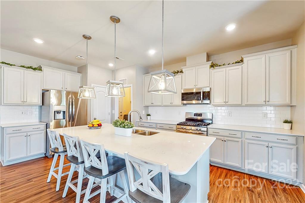 1016 Loggerhead Drive Lancaster, SC 29720 - Photo 4 of 46 a kitchen with stainless steel appliances a stove a sink a kitchen island with chairs and wooden cabinets