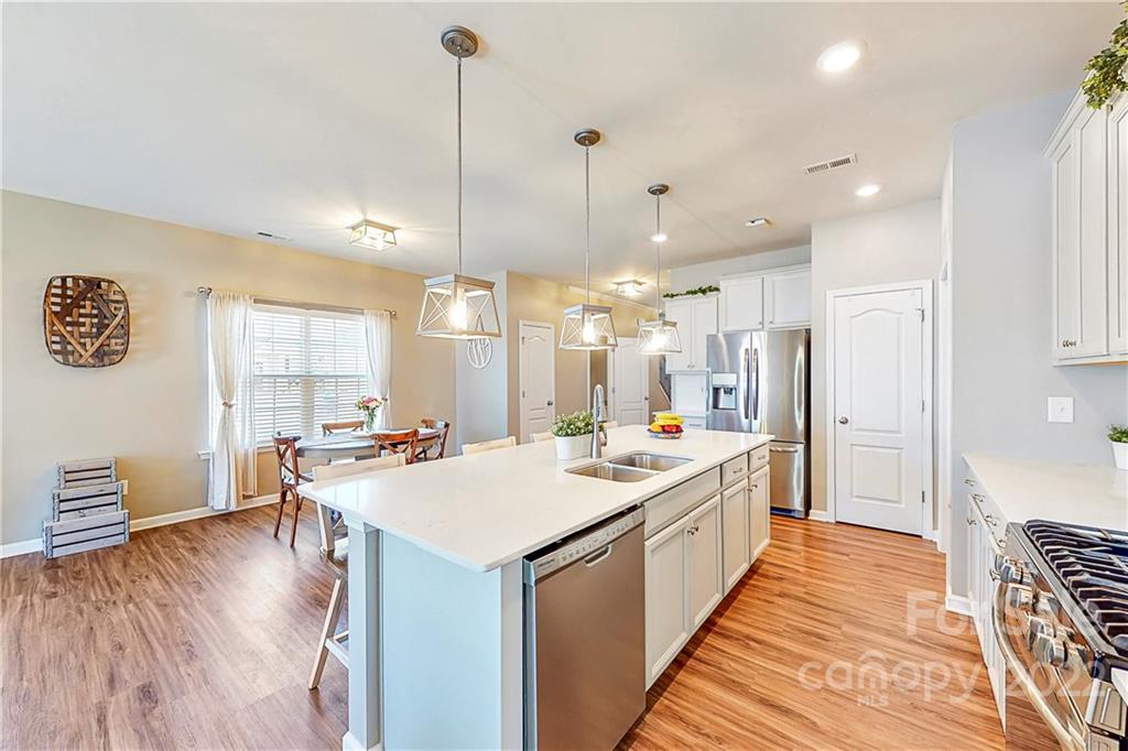 1016 Loggerhead Drive Lancaster, SC 29720 - Photo 7 of 46 a kitchen with a stove a refrigerator a sink dishwasher with a dining table and chairs with wooden floor