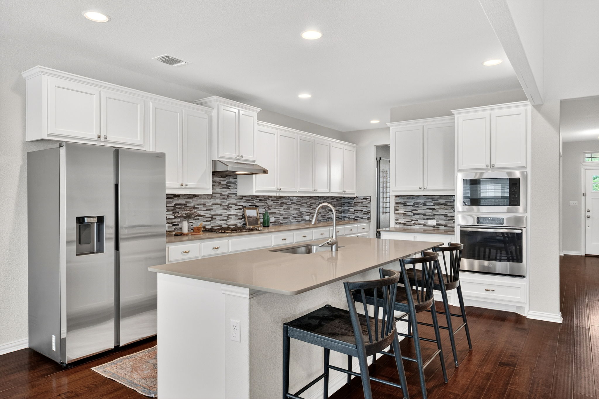 12613 Twisted Root Drive Manchaca, TX 78652 - Photo 7 of 32 a kitchen with stainless steel appliances a refrigerator a stove a sink and white cabinets with wooden floor