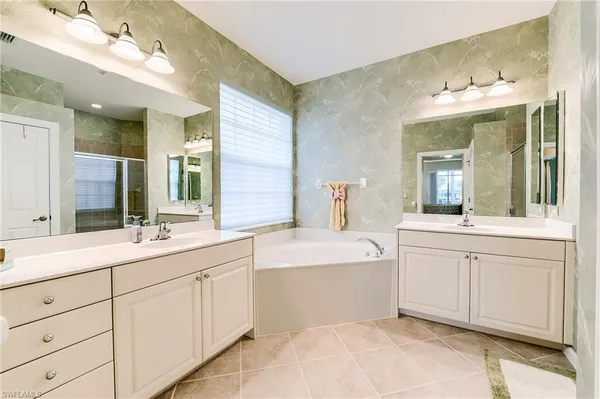 a spacious bathroom with a double vanity sink mirror and bathtub