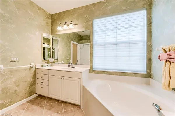a spacious bathroom with a tub sink and mirror