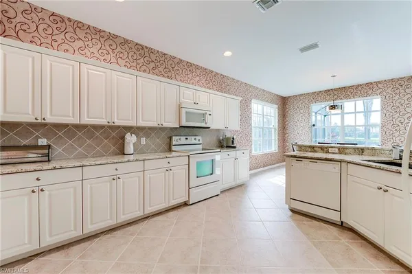 a kitchen with granite countertop white cabinets white stainless steel appliances with a sink and dishwasher