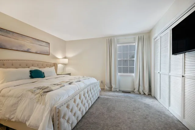 a bedroom with a bed and a flat tv screen on wall