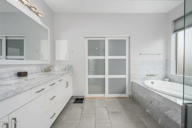 a bathroom with a tub a double vanity sink and mirror