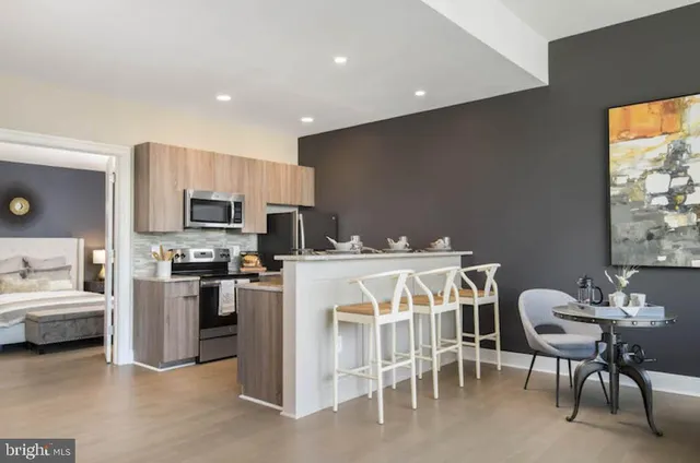a kitchen with stainless steel appliances kitchen island granite countertop a table and chairs in it