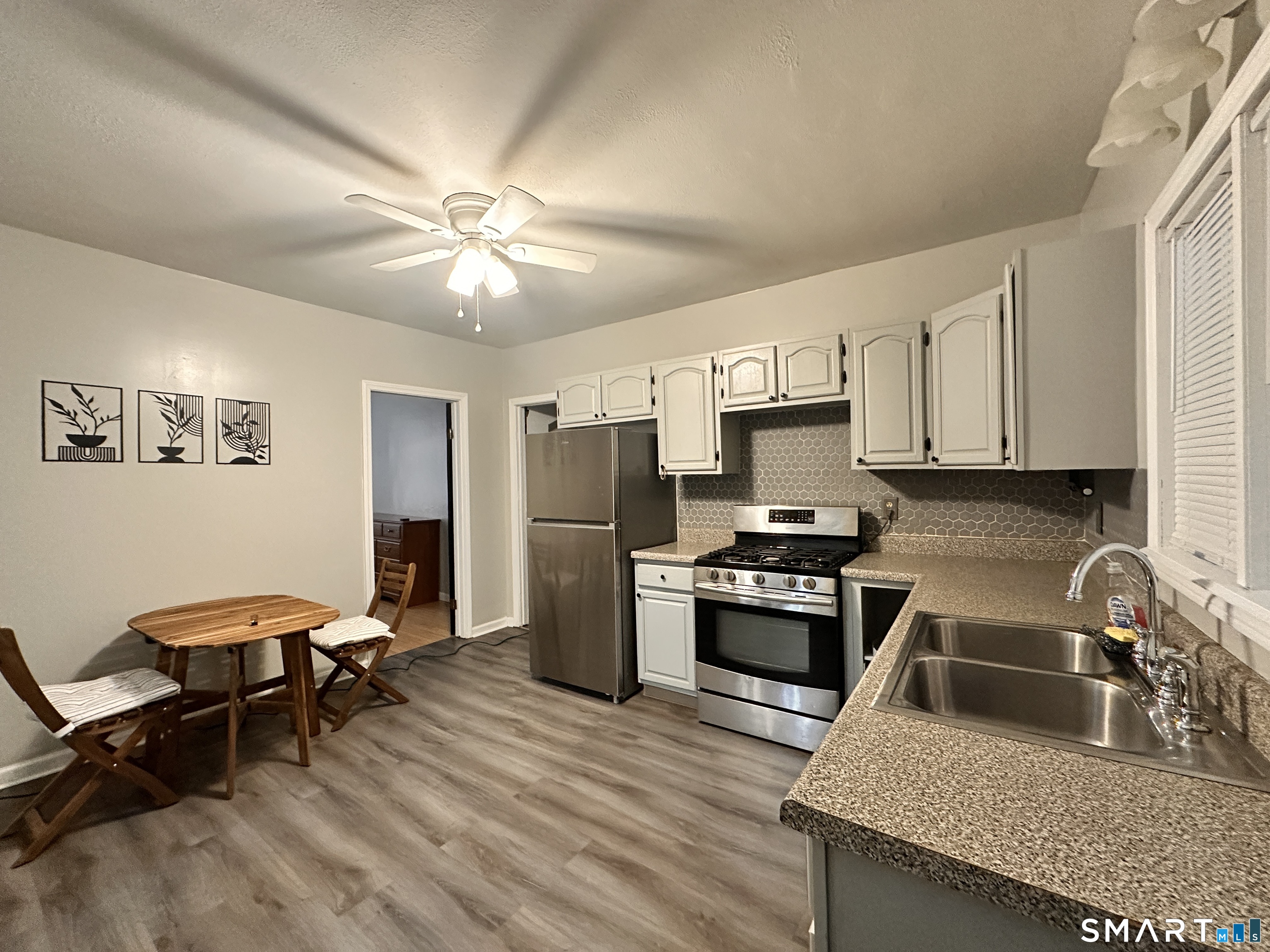 74 Mt Pleasant Street, Unit 2 Derby, CT 06418 - Photo 5 of 19 a kitchen with stainless steel appliances granite countertop a stove top oven a sink a dining table and chairs with wooden floor