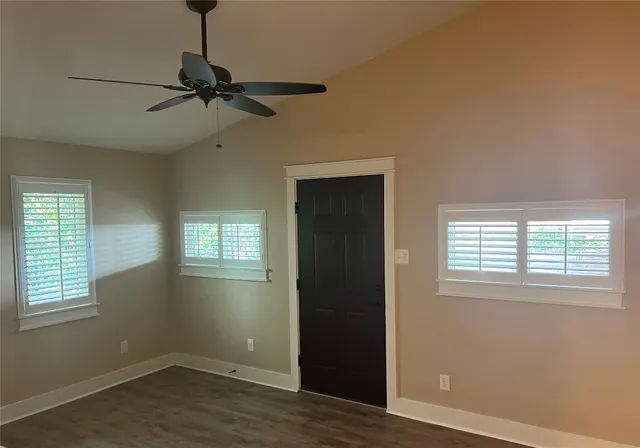 a view of an empty room with wooden floor and windows