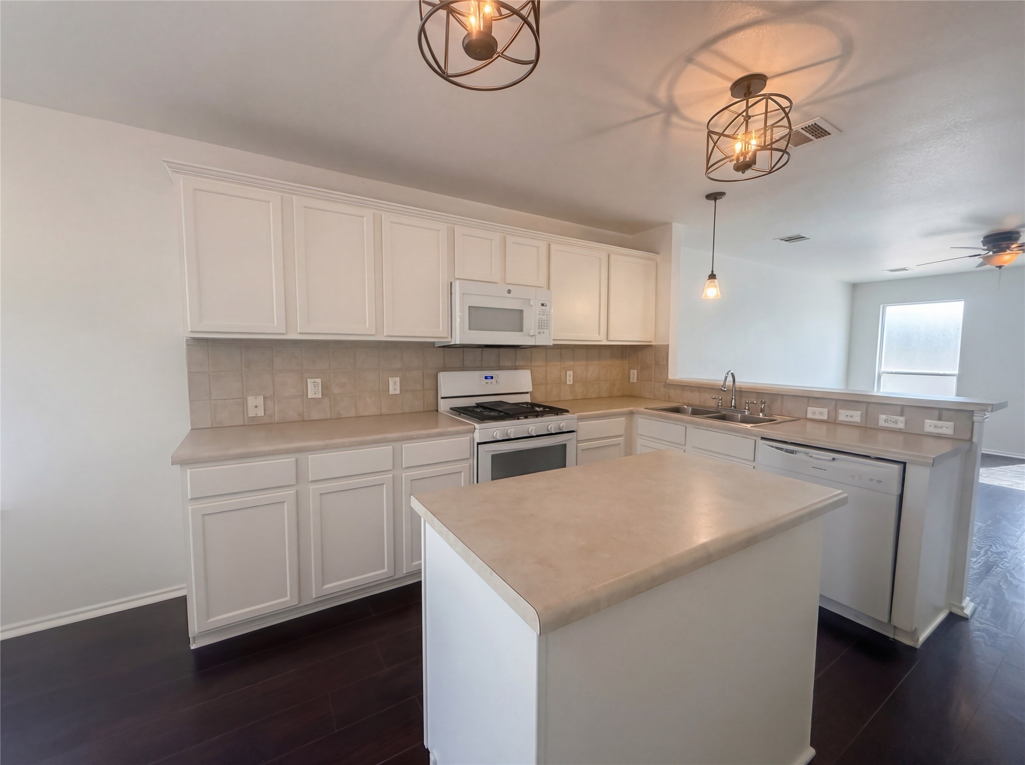110 Strawn Kyle, TX 78640 - Photo 2 of 22 Kitchen featuring white appliances, white cabinetry, light countertops, dark wood-style flooring, and a peninsula