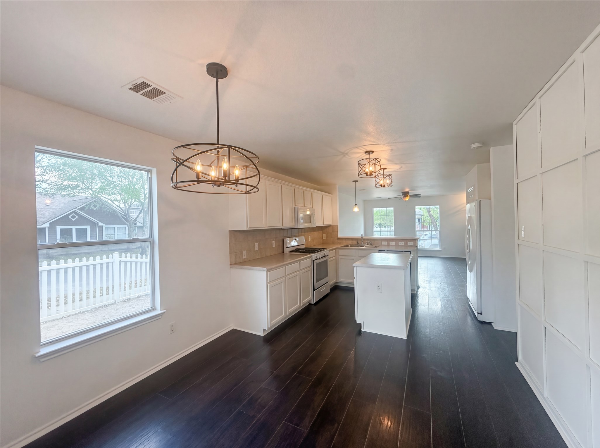 110 Strawn Kyle, TX 78640 - Photo 6 of 22 Kitchen featuring suspended lighting, light countertops, white cabinetry, and white appliances