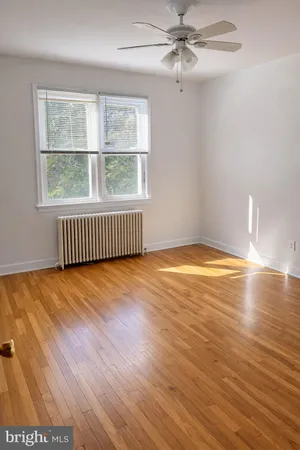 an empty room with wooden floor fan and windows