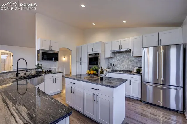a kitchen with stainless steel appliances granite countertop a sink a stove and refrigerator