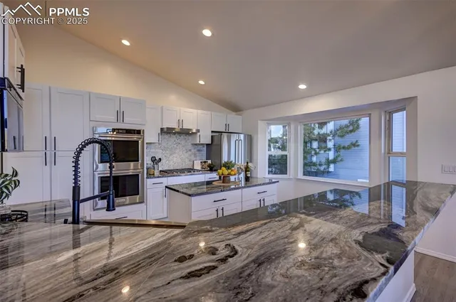 a large kitchen with stainless steel appliances wooden floor and a refrigerator