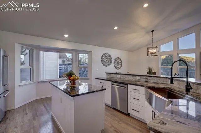 a kitchen with granite countertop a sink cabinets and wooden floor