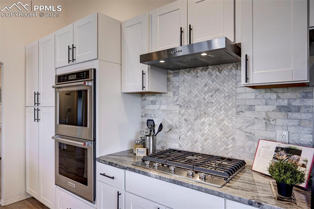 7790 Julynn Road Colorado Springs, CO 80919 - Photo 17 of 50 a kitchen with stainless steel appliances granite countertop a stove and a refrigerator with wooden cabinets