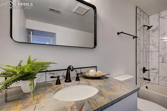 a bathroom with a granite countertop sink a mirror and shower