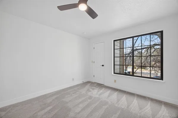 an empty room with windows and ceiling fan