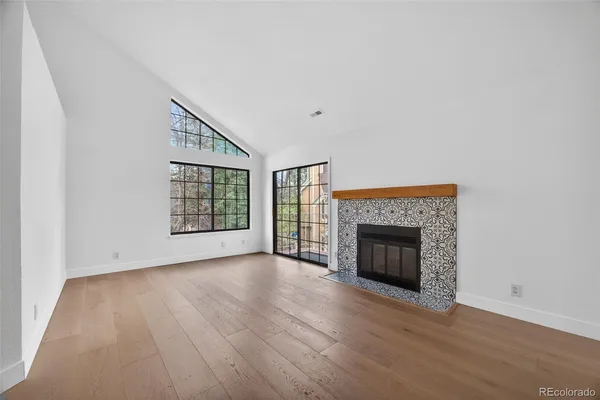 an empty room with wooden floor fireplace and windows