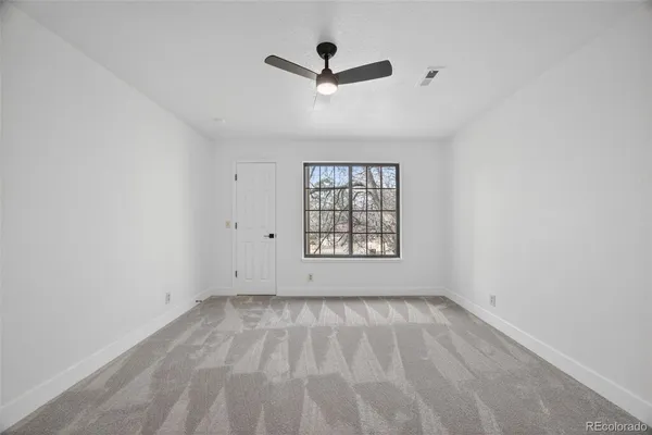 an empty room with ceiling fan and windows