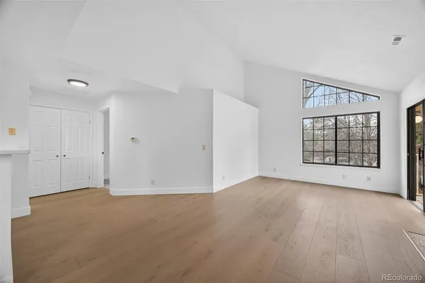 a view of an empty room with a window and wooden floor