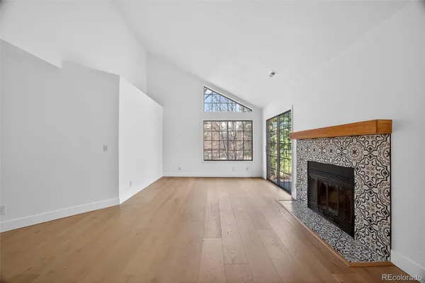 an empty room with windows fireplace and wooden floor