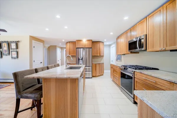 a kitchen with stainless steel appliances granite countertop a stove a sink a microwave a refrigerator and cabinets