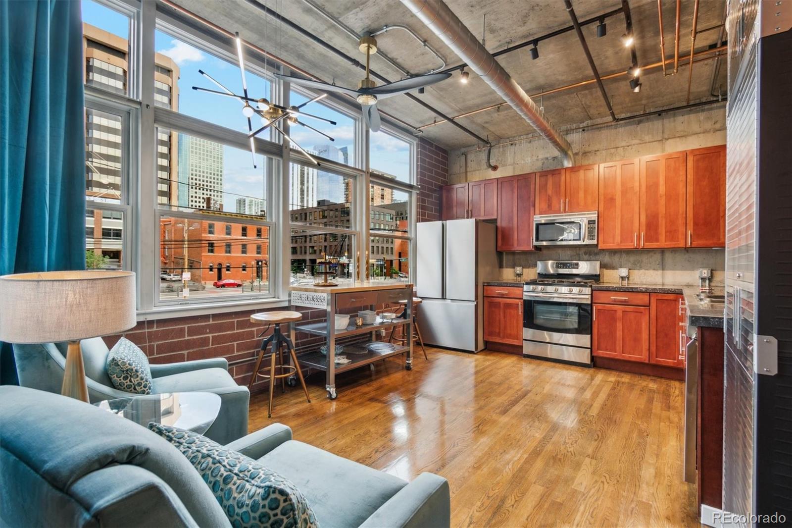 1720 Wazee Street, Unit 2B Denver, CO 80202 - Photo 10 of 17 a kitchen with stainless steel appliances granite countertop a stove a refrigerator a oven with a dining table and chairs with wooden floor