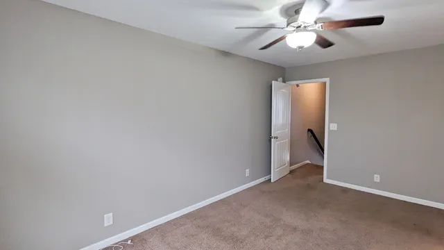 an empty room with a chandelier fan and windows