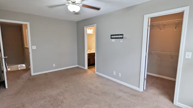 an empty room with closet and a chandelier fan