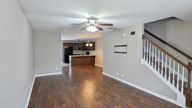 a view of a hallway with wooden floor and a kitchen