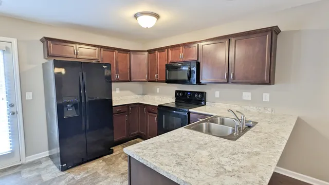 a kitchen with stainless steel appliances granite countertop wooden cabinets a refrigerator and a sink
