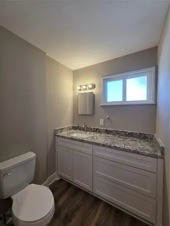 a bathroom with a granite countertop toilet sink and mirror